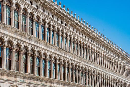 Venice Italy 29 March 2026 View of the Procuratie Vecchie s ornate facade a symphony of arched windows and decorative stonework against a clear blue sky. Venice Italy 29 March 2026 View of the Procuratie Vecchie s ornate facade a symphony of arched windows and decorative stonework against a clear blue sky.