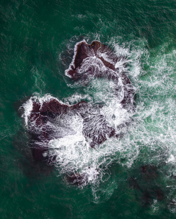 Aerial view of dark rocks in the turquoise Mediterranean Sea with white crashing waves near the historic coastline of the Old port of Jaffa in Tel Aviv Yafo Tel Aviv District Israel.