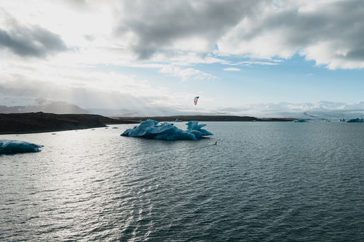 Aerial view of Jokulsarlon glacier lagoon with floating icebergs and a kite surfer on the water under a cloudy sky in Sveitarfelagid Hornafjordur Iceland. Aerial view of Jokulsarlon glacier lagoon with floating icebergs and a kite surfer on the water under a cloudy sky in Sveitarfelagid Hornafjordur Iceland.