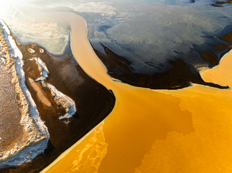 Aerial view of geothermal landscape in Reykjanesbaer featuring dark volcanic sand vibrant yellow mineral deposits and patches of snow under soft light in Reykjanesbaer Iceland. Aerial view of geothermal landscape in Reykjanesbaer featuring dark volcanic sand vibrant yellow mineral deposits and patches of snow under soft light in Reykjanesbaer Iceland.
