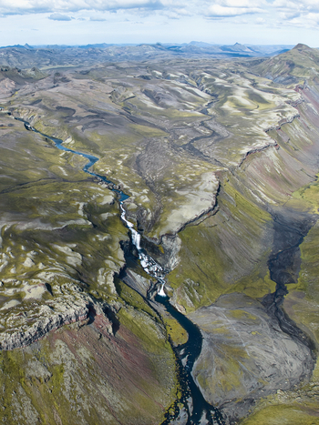 Aerial view of the volcanic canyon of Eldgja with its winding river and waterfall cutting through the rugged mossy landscape of Kirkjubaejarklaustur Skaftarhreppur Iceland. Aerial view of the volcanic canyon of Eldgja with its winding river and waterfall cutting through the rugged mossy landscape of Kirkjubaejarklaustur Skaftarhreppur Iceland.