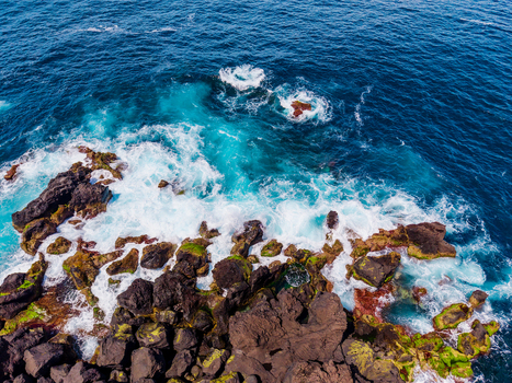 Aerial view of the rugged dark volcanic rocks meeting the frothy turquoise waves of the Atlantic Pico Azores Portugal. Aerial view of the rugged dark volcanic rocks meeting the frothy turquoise waves of the Atlantic Pico Azores Portugal.
