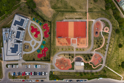 Aerial view of a modern playground and sports complex with a basketball court walking paths and a parking lot in Brno South Moravian Region Czechia.