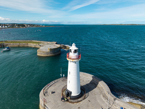Aerial view of Donaghadee Harbour lighthouse with white tower and red railing on a stone pier in the Irish Sea in Donaghadee Northern Ireland United Kingdom. Aerial view of Donaghadee Harbour lighthouse with white tower and red railing on a stone pier in the Irish Sea in Donaghadee Northern Ireland United Kingdom.