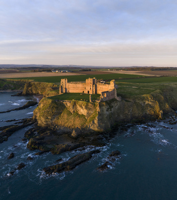 Aerial view of the historic Tantallon Castle ruins perched on high cliffs overlooking the North Sea at sunset North Berwick Scotland United Kingdom.