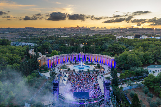 Attard Malta 20 September 2026 Aerial view of Park Nazzjonali Ta Qali during a music festival with a large crowd gathered before a stage illuminated by purple lights at sunset. Attard Malta 20 September 2026 Aerial view of Park Nazzjonali Ta Qali during a music festival with a large crowd gathered before a stage illuminated by purple lights at sunset.