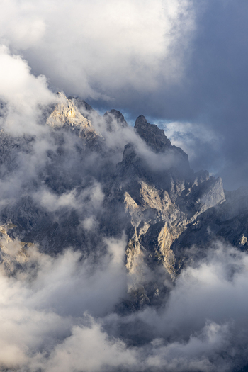 View of rugged mountain peaks piercing through a sea of swirling clouds bathed in soft light a symphony of textures Picos de Europa Asturias Spain. View of rugged mountain peaks piercing through a sea of swirling clouds bathed in soft light a symphony of textures Picos de Europa Asturias Spain.