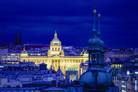 Aerial view of the illuminated National Museum surrounded by historic rooftops and city lights under a deep blue night sky Prague Prague Czechia. Aerial view of the illuminated National Museum surrounded by historic rooftops and city lights under a deep blue night sky Prague Prague Czechia.