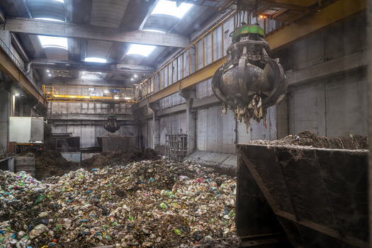 View of the Forsu Iren waste treatment plant with a large mechanical grabber over piles of organic waste inside an industrial facility Reggio nell Emilia Emilia Romagna Italy. View of the Forsu Iren waste treatment plant with a large mechanical grabber over piles of organic waste inside an industrial facility Reggio nell Emilia Emilia Romagna Italy.