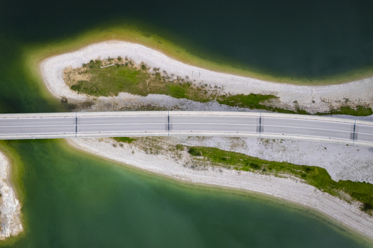 Aerial view of a bridge cutting a path through the vibrant turquoise waters and lush green isles of Sylvensteinspeicher Bavaria Germany. Aerial view of a bridge cutting a path through the vibrant turquoise waters and lush green isles of Sylvensteinspeicher Bavaria Germany.
