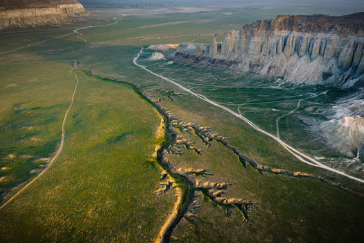 Aerial view of Airakty rock formations rising above the green plains and winding dirt paths in Shetpe Mangystau Region Kazakhstan.