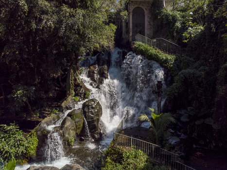 Aerial view of La Espumita waterfall surrounded by lush green forest stone structures and metal railings in Uruapan Michoacan Mexico.