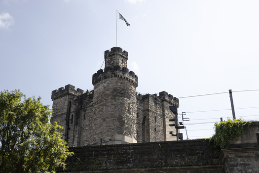 View of the historic stone keep of Newcastle Castle with battlements and a flag flying against a clear blue sky in Newcastle upon Tyne England United Kingdom. View of the historic stone keep of Newcastle Castle with battlements and a flag flying against a clear blue sky in Newcastle upon Tyne England United Kingdom.
