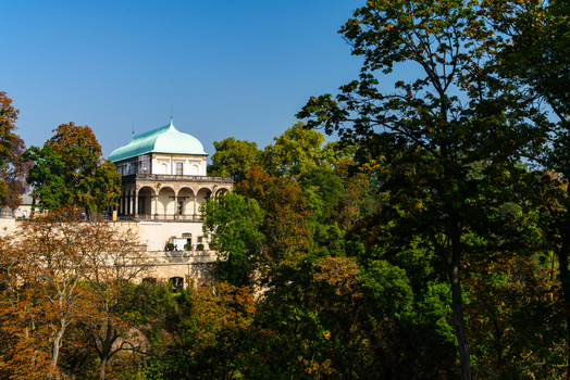 View of the Renaissance Queen Anne s Summer Palace with its distinctive green copper roof and arched loggia nestled among lush autumn trees in Prague Prague Czechia.