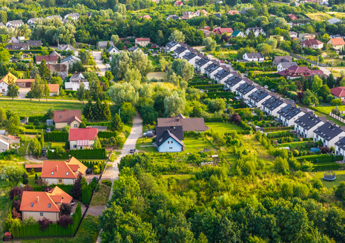 Aerial view of a residential neighborhood featuring detached houses with red and dark roofs lush green gardens and narrow roads in Kowale Pomeranian Voivodeship Poland. Aerial view of a residential neighborhood featuring detached houses with red and dark roofs lush green gardens and narrow roads in Kowale Pomeranian Voivodeship Poland.