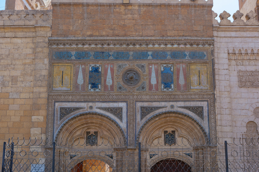 View of the ornate facade of Al Azhar Mosque featuring intricate stone carvings and colorful mosaics in Cairo Egypt. View of the ornate facade of Al Azhar Mosque featuring intricate stone carvings and colorful mosaics in Cairo Egypt.
