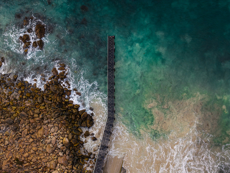 Aerial view of Canal Rocks Bridge extending into the turquoise Indian Ocean waters with rugged rocky coastline and crashing waves in Yallingup Western Australia Australia.