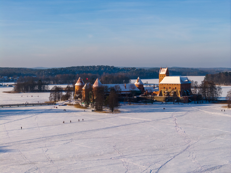 Aerial view of Trakai Island Castle with its red brick towers surrounded by a frozen snow covered lake and people walking on the ice in Trakai Vilniaus apskritis Lithuania.