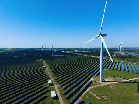 Aerial view of Chelveston Wind Farm featuring white wind turbines and vast rows of solar panels under a clear blue sky in Wellingborough England United Kingdom. Aerial view of Chelveston Wind Farm featuring white wind turbines and vast rows of solar panels under a clear blue sky in Wellingborough England United Kingdom.