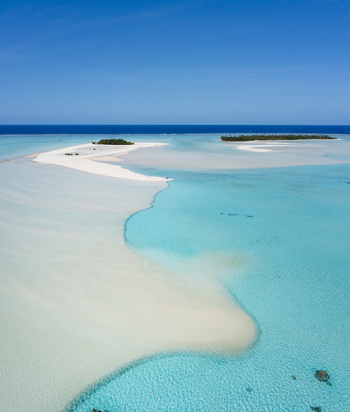 Aerial view of the pristine Aitutaki lagoon with its white sandbars vibrant turquoise water and coral reefs under a clear blue sky in Aitutaki Cook Islands. Aerial view of the pristine Aitutaki lagoon with its white sandbars vibrant turquoise water and coral reefs under a clear blue sky in Aitutaki Cook Islands.