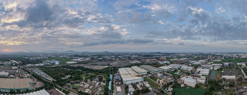 Aerial view of the industrial zone featuring large factory buildings warehouses and parking lots under a dramatic cloudy sky at sunset in Chakan Maharashtra India.