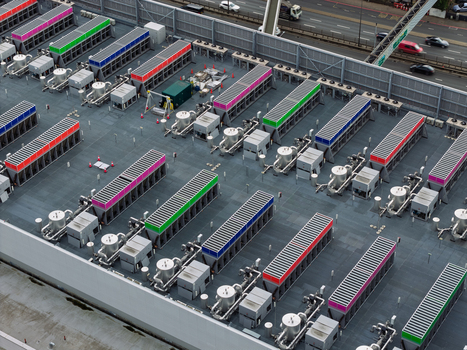 Aerial view of a data center rooftop featuring rows of colorful cooling units and industrial ventilation systems with a road visible in the background in the United Kingdom.