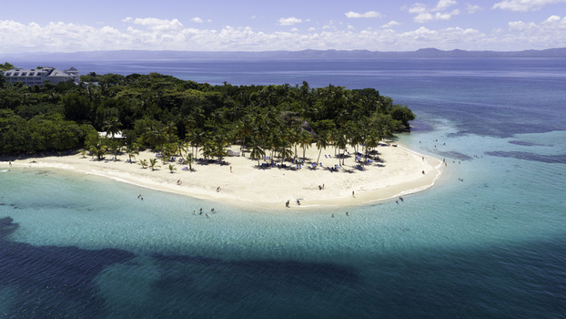 Aerial view of Cayo Levantado Beach with white sand palm trees and turquoise water featuring resort buildings and people swimming in Samana SAMANA Dominican Republic. Aerial view of Cayo Levantado Beach with white sand palm trees and turquoise water featuring resort buildings and people swimming in Samana SAMANA Dominican Republic.