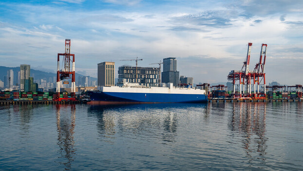 View of the Cebu Port Authority with a cargo ship docked alongside industrial cranes shipping containers and the city skyline in Cebu City Central Visayas Philippines. View of the Cebu Port Authority with a cargo ship docked alongside industrial cranes shipping containers and the city skyline in Cebu City Central Visayas Philippines.