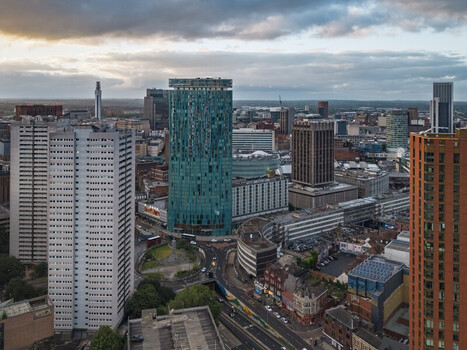 Aerial view of the Birmingham city center skyline featuring the iconic green Rotunda building surrounded by modern high rise architecture and urban roads in Birmingham England United Kingdom.