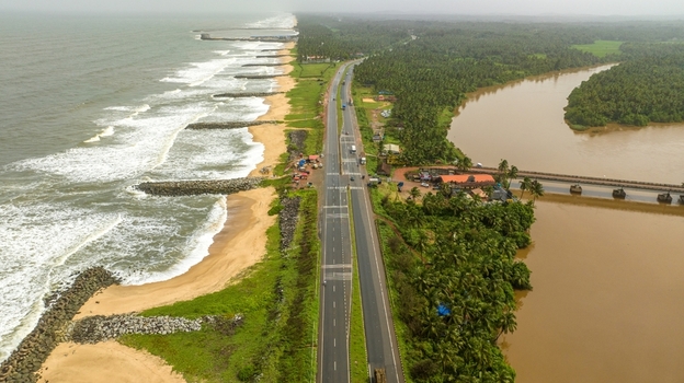 Aerial view of Maravanthe beach featuring the Arabian Sea on one side and the Souparnika River on the other separated by a coastal highway in Maravanthe Karnataka India. Aerial view of Maravanthe beach featuring the Arabian Sea on one side and the Souparnika River on the other separated by a coastal highway in Maravanthe Karnataka India.