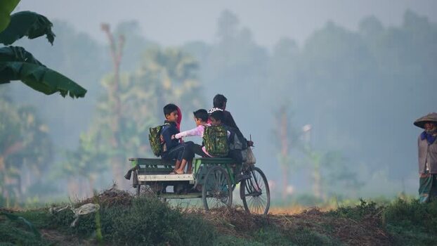 View of children on a cycle van in a misty rural area Bangladesh. View of children on a cycle van in a misty rural area Bangladesh.