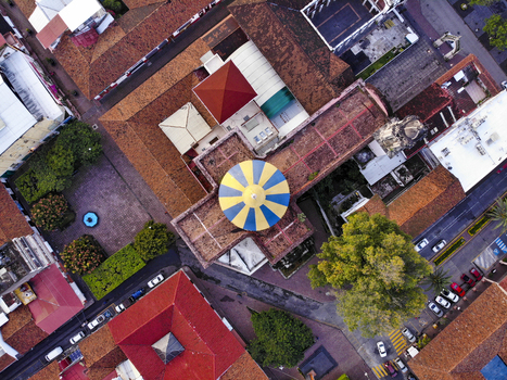 Aerial view of the Centro district in Uruapan featuring the blue and yellow church dome terracotta rooftops lush trees and city streets Uruapan Michoacan Mexico.