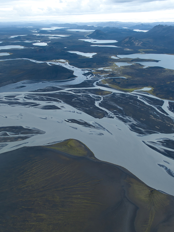 Aerial view of the braided river system near Skyggnisvatn showcasing glacial waters dark volcanic terrain and mossy hills Hella Rangarthing ytra Iceland. Aerial view of the braided river system near Skyggnisvatn showcasing glacial waters dark volcanic terrain and mossy hills Hella Rangarthing ytra Iceland.