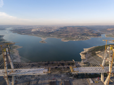 Aerial view of the Yavuz Sultan Selim Bridge under construction featuring large cable stayed towers construction cranes and a wide expanse of water in Istanbul Istanbul Turkiye.