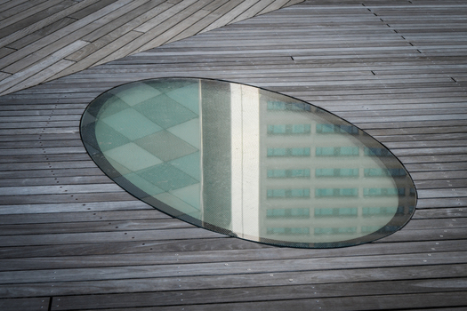 View of an oval glass skylight reflecting a modern office building set into a weathered wooden deck Vilnius Vilnius County Lithuania. View of an oval glass skylight reflecting a modern office building set into a weathered wooden deck Vilnius Vilnius County Lithuania.