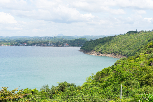 View of Jungle Beach and the turquoise waters of the bay surrounded by lush green hills and tropical vegetation in Unawatuna Southern Province Sri Lanka.
