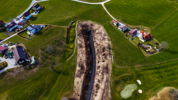Aerial view of emerald green meadows meeting quaint villages a dark tunnel cutting through the landscape Windischgarsten Upper Austria Austria. Aerial view of emerald green meadows meeting quaint villages a dark tunnel cutting through the landscape Windischgarsten Upper Austria Austria.