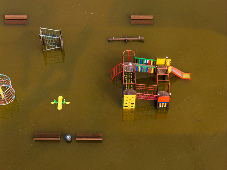 Aerial view of a flooded children s playground with colorful climbing frames and wooden benches submerged in murky brown water in Kedainiai Kaunas County Lithuania. Aerial view of a flooded children s playground with colorful climbing frames and wooden benches submerged in murky brown water in Kedainiai Kaunas County Lithuania.
