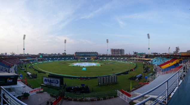 Lahore Pakistan 17 February 2024 View of Gaddafi Stadium a cricket ground with a green pitch colorful seating tiers and tall floodlight towers under a clear sky.