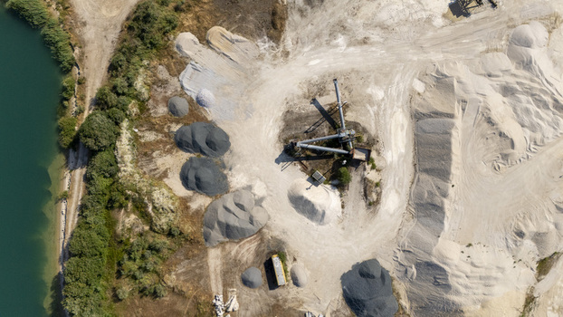 Aerial view of the Extraccion de aridos Lima S.L. quarry featuring piles of sand and gravel industrial processing machinery and a nearby river in Vilarino das Poldras Ourense Spain. Aerial view of the Extraccion de aridos Lima S.L. quarry featuring piles of sand and gravel industrial processing machinery and a nearby river in Vilarino das Poldras Ourense Spain.