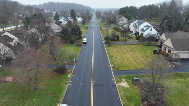 Aerial view of a quiet suburban street lined with residential houses bare trees and light snow on the ground in Neffsville Pennsylvania United States.