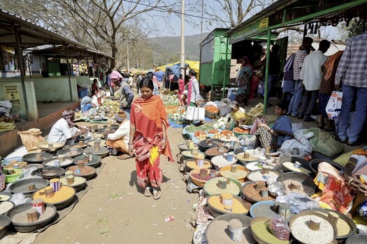 Odisha India 26 March 2026 View of a vibrant market scene unfolds with vendors displaying colorful spices and produce under simple shelters as a woman in red walks through the bustling ground. Odisha India 26 March 2026 View of a vibrant market scene unfolds with vendors displaying colorful spices and produce under simple shelters as a woman in red walks through the bustling ground.