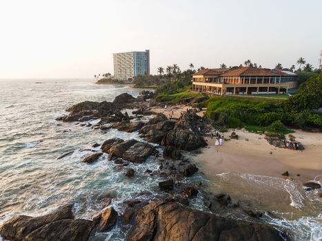 Aerial view of the rocky coastline and sandy beach with a luxury resort and people walking along the shore in Galle Southern Province Sri Lanka. Aerial view of the rocky coastline and sandy beach with a luxury resort and people walking along the shore in Galle Southern Province Sri Lanka.