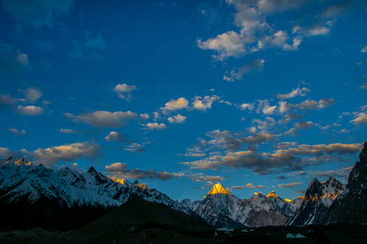 View of the snow capped peak of Gasherbrum IV glowing in golden sunset light under a blue cloudy sky in Skardu Gilgit Pakistan. View of the snow capped peak of Gasherbrum IV glowing in golden sunset light under a blue cloudy sky in Skardu Gilgit Pakistan.