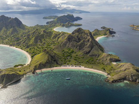 Aerial view of Padar Island featuring dramatic green hills pristine sandy beaches and turquoise waters in Komodo East Nusa Tenggara Indonesia. Aerial view of Padar Island featuring dramatic green hills pristine sandy beaches and turquoise waters in Komodo East Nusa Tenggara Indonesia.