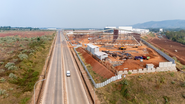 Aerial view of the Kawasan Industri Terpadu Batang construction site featuring steel framework heavy machinery and a long highway in Kecamatan Gringsing Jawa Tengah Indonesia.