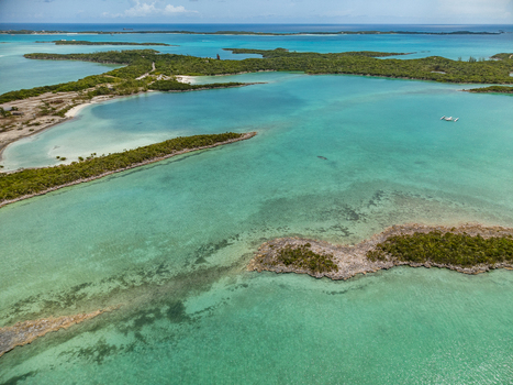 Aerial view of Crab Cay featuring turquoise waters lush green tropical islands and coral reefs under a clear sky in Exuma Exuma The Bahamas. Aerial view of Crab Cay featuring turquoise waters lush green tropical islands and coral reefs under a clear sky in Exuma Exuma The Bahamas.