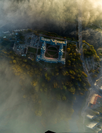 Aerial view of Jelgava Palace surrounded by morning fog and lush trees with a river and bridge nearby in Jelgava Latvia. Aerial view of Jelgava Palace surrounded by morning fog and lush trees with a river and bridge nearby in Jelgava Latvia.