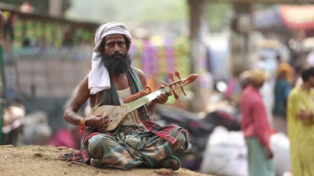 View of a Baul musician playing a traditional instrument Bangladesh.