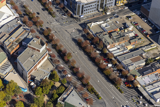 Aerial view of Lonsdale Street featuring commercial buildings rows of trees with autumn foliage and parked vehicles in Dandenong Victoria Australia.